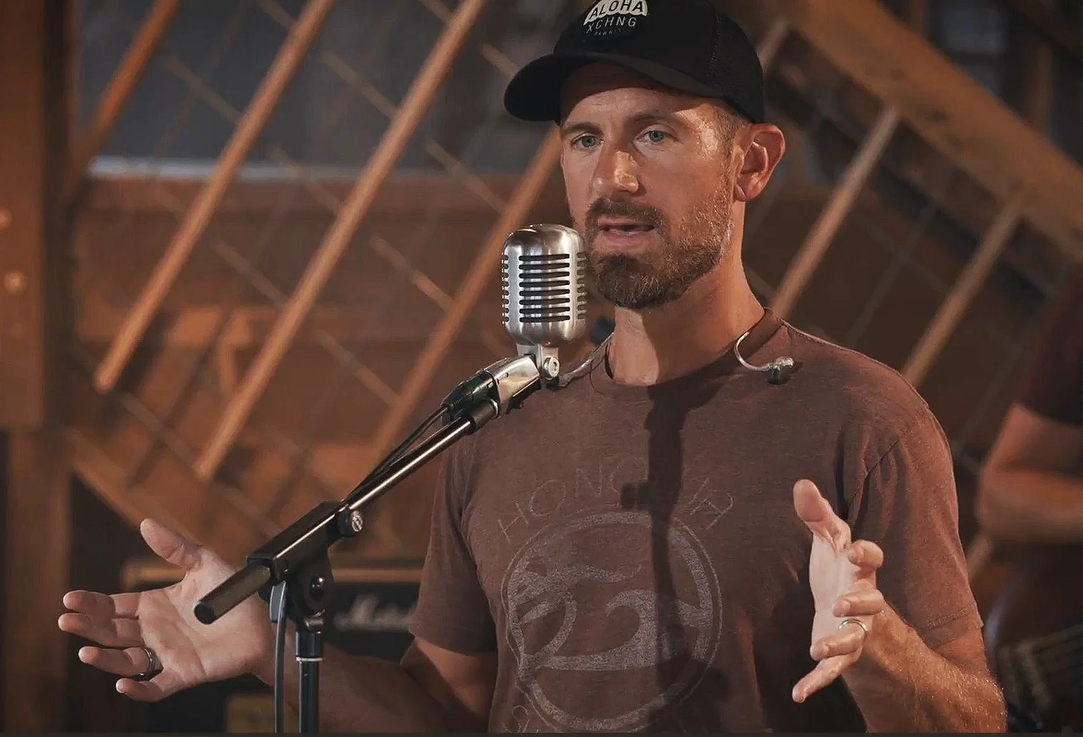 Drew Scholl speaking at a vintage microphone